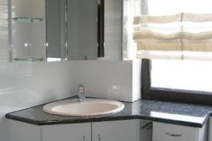 Badezimmermöbel mit Spiegeleckschrank über Eck in HPL- Rundkante weiß mit Granit- Waschtischplatte nach Maß