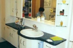 Badezimmermöbel mit 3D-Spiegelschrank- Überbau in Rundkantenfronten HPL Perlmutweiß. Waschtisch und Kranzplatte in HPL Granitschwarz belegt