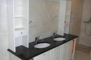 Badezimmer- Unterschränke mit Weißlackfront unter der bauseitigen Granitplatte nebst den gemauerten Zwischennischen eingepasst. Aufsatzregale mit Spiegel- Überbau in Stilart