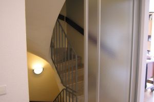 Treppenaufgang Windfang als Gleittüren- Raumteiler Alu-A17 mit ESG Mastercaree Ganzglasfüllung