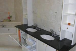 Badezimmer- Unterschränke mit Weißlackfront unter der bauseitigen Granitplatte nebst den gemauerten Zwischennischen eingepasst. Aufsatzregale mit Spiegel- Überbau in Stilart