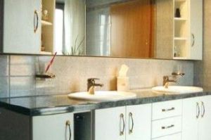 Badezimmermöbel mit 3D-Spiegelüberbau in Rundkantenfronten HPL Esche Weiß. Waschtisch und Kranzplatte in HPL Granit schwarz belegt