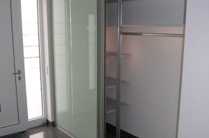 Moderne Garderobe als Alu-Einrichtungssystem mit Tabelaren in Lichtgrau und Alu- Gleittüren rückseitig lackiertes Glas