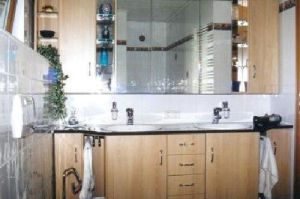 Badezimmermöbel mit Spiegelschrank- Überbau in Rundkantenfronten HPL Apfel. Waschtisch und Kranzplatte in HPL Granit schwarz belegt