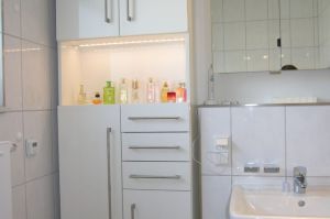Badezimmerschrank in weiß Brilliantglanz mit Sensor- Innenbeleuchtung und sehr langen Edelstahl- Relinggriffen auf Kundenwunsch