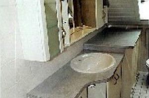 Badezimmermöbel mit 3D-Spiegelüberbau in Rundkantenfronten HPL perlmut Weiß. Waschtisch und Kranzplatte in HPL Granit hellgrau belegt