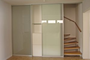 Treppenhaus Windfang als Schrank- Raumlösung in weiß matt mit Türen grifflos,   und geöffneter Gleittüre mit Mattglasfüllung zum begehen des Treppenhauses zum OG