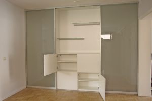 Treppenhaus Windfang als Schrank- Raumlösung in weiß matt mit Türen grifflos,   und Gleittüren mit Mattglasfüllung zum begehen des Treppenhauses.
