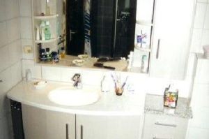 Badezimmermöbel mit Spiegelschrank- Überbau in Rundkantenfronten HPL Esche grau. Waschtisch und Kranzplatte in HPL Granit belegt